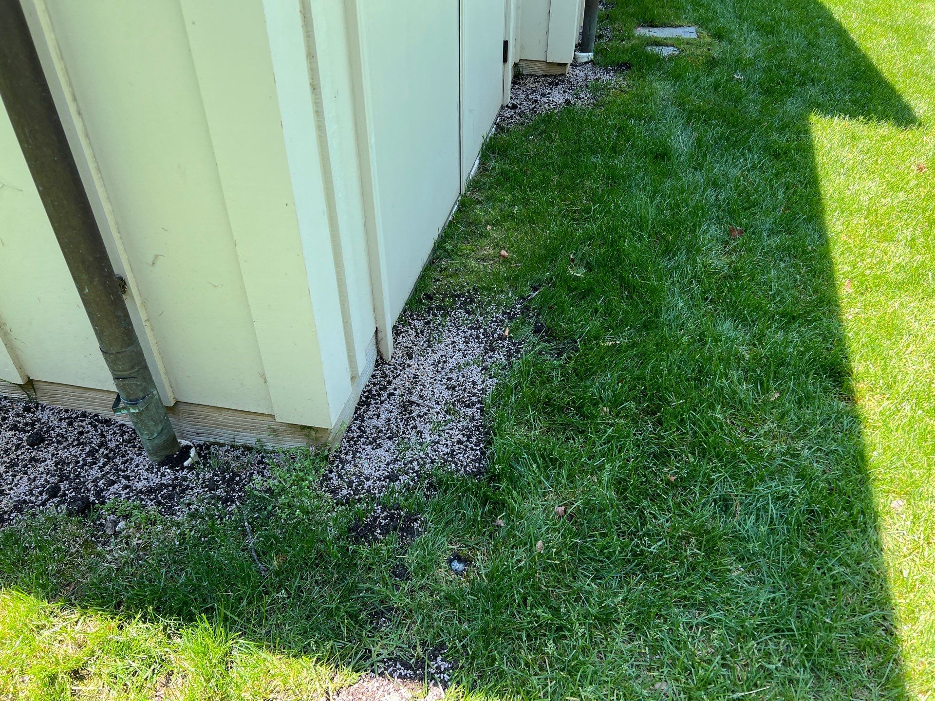 Sump Pump Drainage — exterior discharge outlet with gravel at building corner